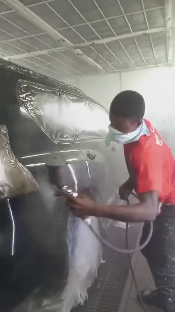 Painter spraying the black Toyota Land Cruiser in the spray booth