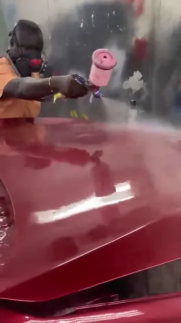 Painter in a respirator spraying red paint on the bonnet of the Toyota RAV4